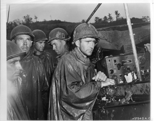 demons:Men of the US Army’s 77th Infantry Division listening to news of Germany’s unconditional surr