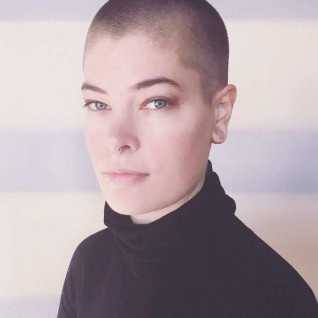 self portrait of artist with shaved head and black turtleneck in front of large pastel violet amd cream stripe painting. 