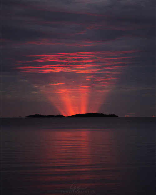 Red Crepuscular Rays from an Eclipse  What&rsquo;s happening behind that island? Things both exp