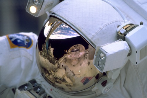 humanoidhistory:SPACEMAN 1999 — The Earth and cargo bay of the Space Shuttle Discovery are reflected