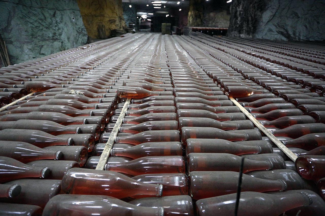 CAVA PROFUNDA. En el fondo de una enorme y antigua mina, a tan sólo unos kilómetros de la línea del frente, cientos de miles de botellas de vino espumoso aguardan en un laberinto de túneles y bodegas, en Ucrania. Es un refugio antibombas de 25...