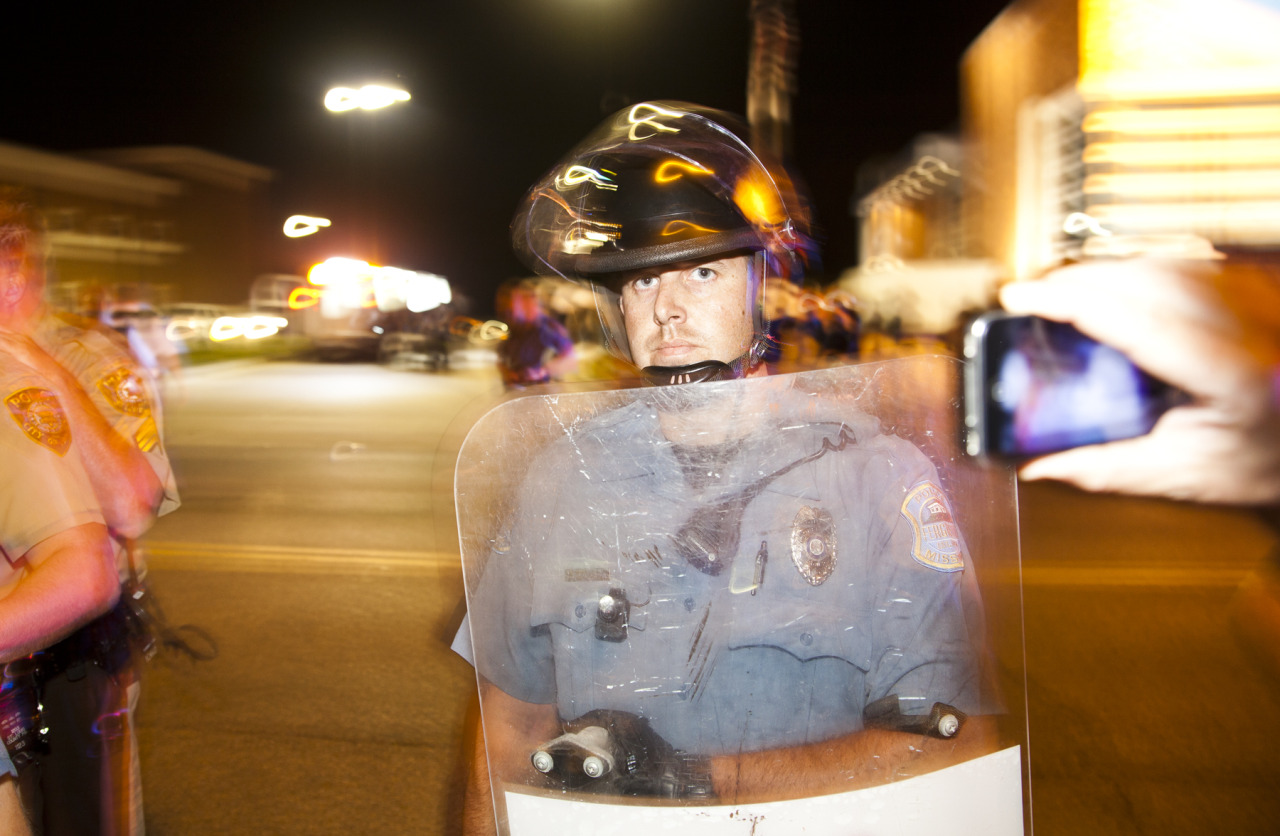 A Ferguson Police Officer stares down people on the sidewalk as police prepare for arrests on Sunday night.
www.AmplifyFerguson.com
Ferguson Police Department ✚ September, 2014