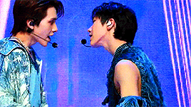 A gif from their performance at MCountdown. Ten is wearing a distressed blue yarn vest and Hendery is wearing a light blue patterned jacket.