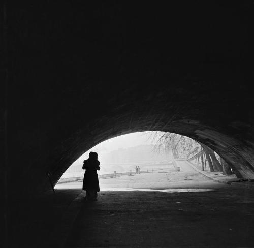 Fred van SchagenRomantic Paris - A courting couple kissing under a bridge on the bank of the Seine, 