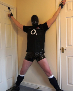 heavybondage:  A ‘Prisoner’ Spreadeagle wearing England Canterbury Rugby Kit, Adidas trainers and tight black PVC shorts. A tight rubber hood was pulled over the ‘Prisoner’s’ head and he was silenced with a large penis gag. More like this at