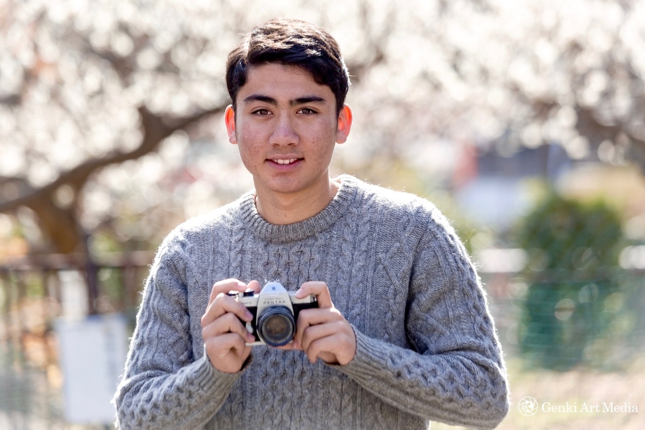 <p><b>Digitally oriented teen with analog camera with plum blossom backdrop.</b></p>