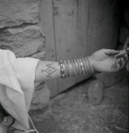 mydearalgeria:Algeria. Chaouie woman showing her tattooed arm and bracelets - 1950.Jacques Faublée.