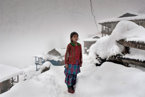 A local girl stares at the Himalayan mountain peaks after a big snowfall caused her village to lose 