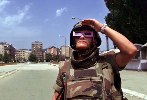 humanoidhistory:A French soldier, part of NATO’s peacekeeping force in Kosovo, watches a solar eclip
