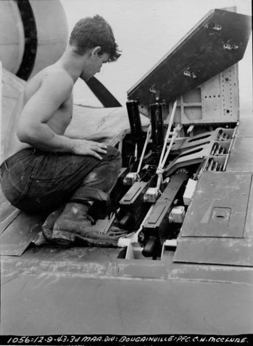 Marine Pfc C.H. McClure servicing the three Browning M2 .50 caliber machine guns in the right wing o