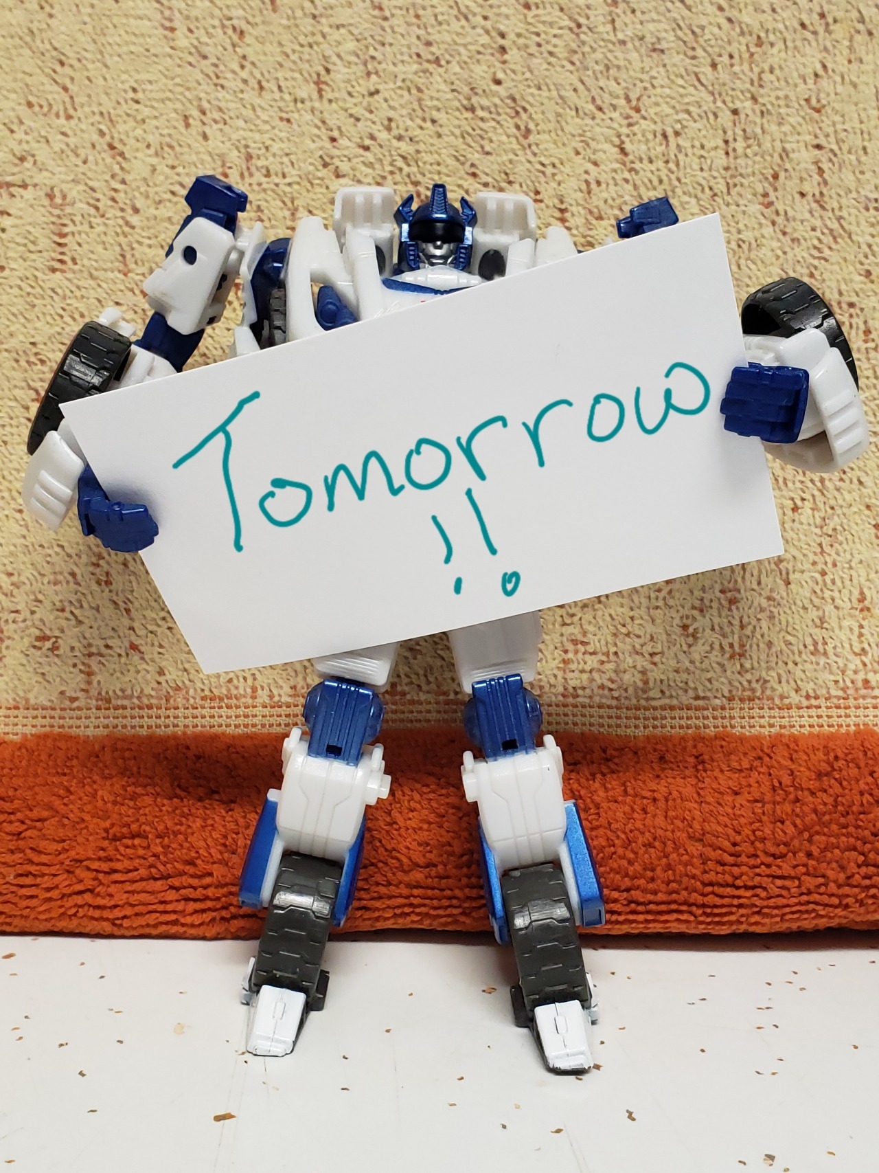 An action figure of the War For Cybertron version of Autobot Jazz, holding a white card reading: Tomorrow!!