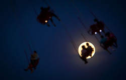 nprfreshair:  The Atlantic’s InFocus Blog:  People ride the Luna Park Swing Ride as the Supermoon rises on Coney Island, on June 22, 2013.  