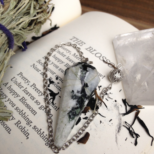 Rainbow moonstone pendulum with sage and a quartz pyramid.