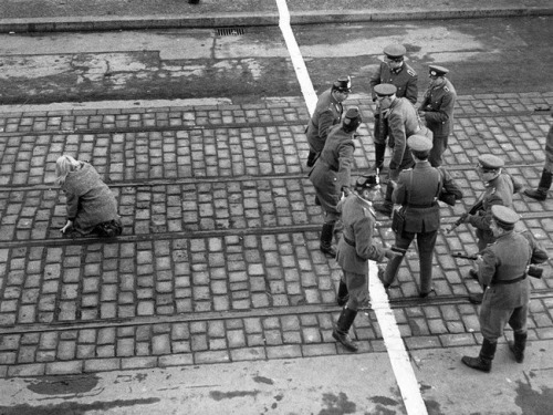 West and East German guards have a brief stare down after a young woman runs across the border in Be