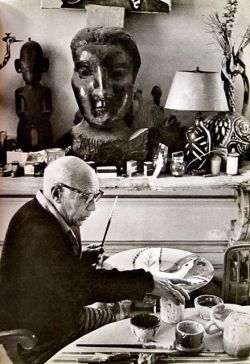 Picasso painting ceramics at the dinner table.