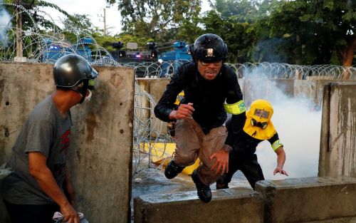 A demonstrator jumps over a barricade during an anti-government protest as lawmakers debate on const