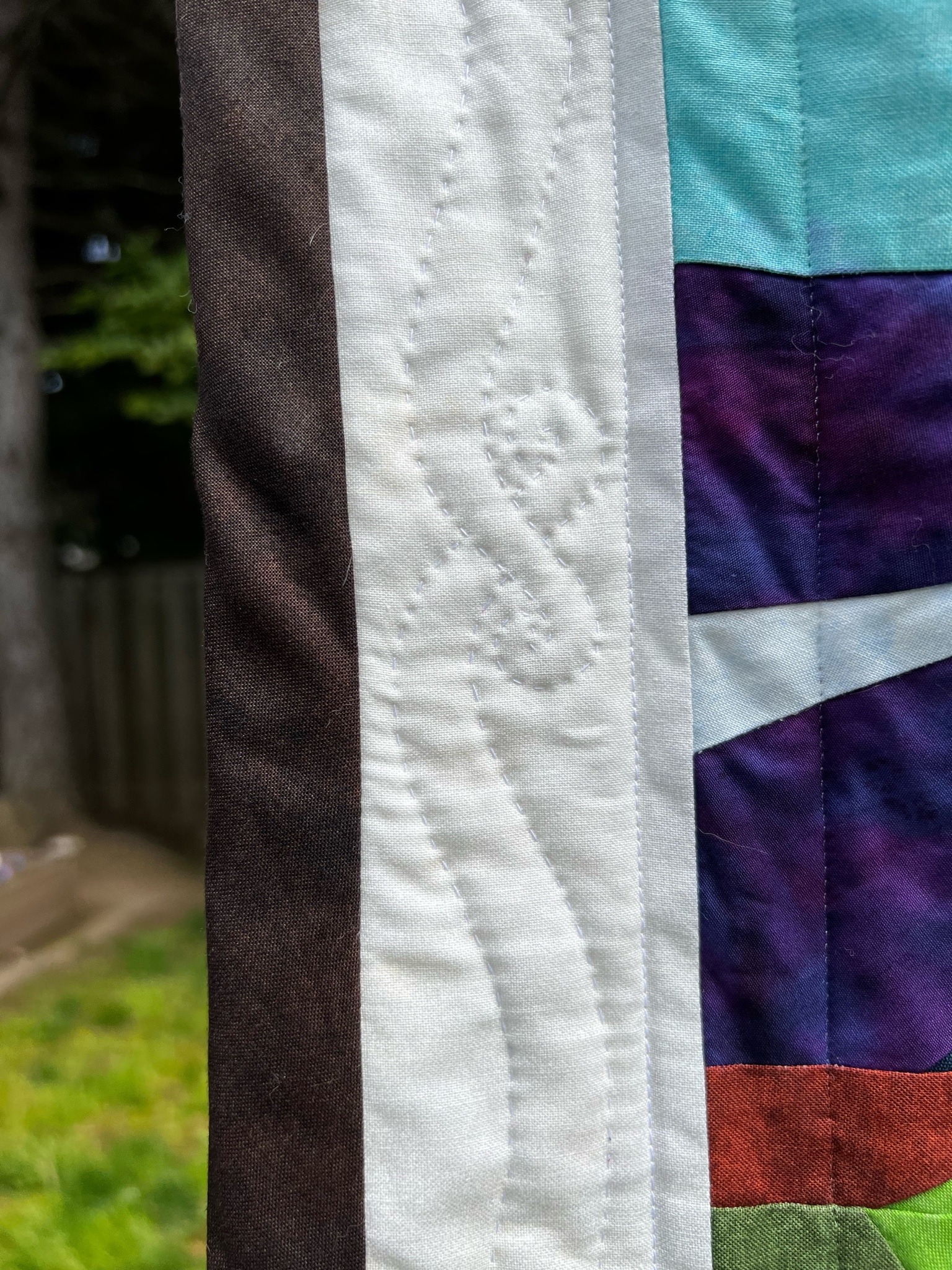 detail of the above quilt side border, white stitching on white fabric in a pattern depicting tentacles curled over each other