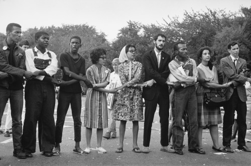 [Photo: nine marchers link arms while singing during the March on Washington in 1963. Marian Wright 
