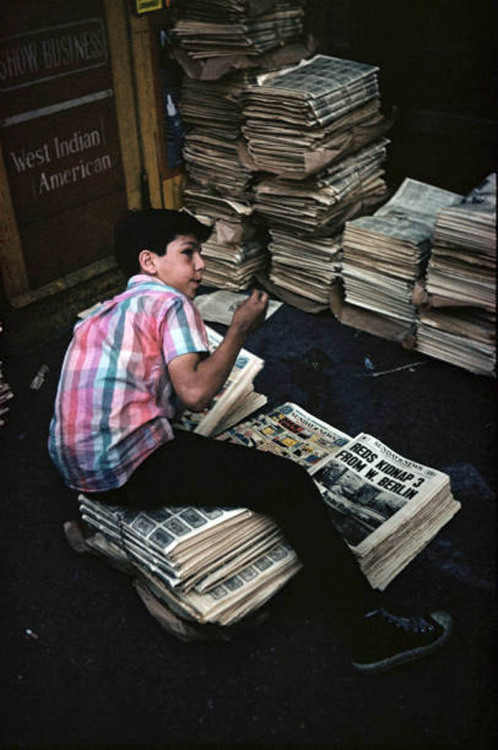 A newspaper boy with copies of the Sunday News, 1952. The headline “Reds Kidnap 3 From W. Berlin” re