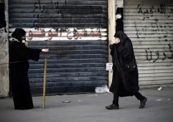 history-does-not-suck:  A Bahraini woman wearing a tear gas mask tries to treat a woman affected by tear gas during clashes with riot police following the funeral of Ahmed Abdul Ameer in the village of Sanabis, west of Manama, on Nov. 30. Abdul Ameer,