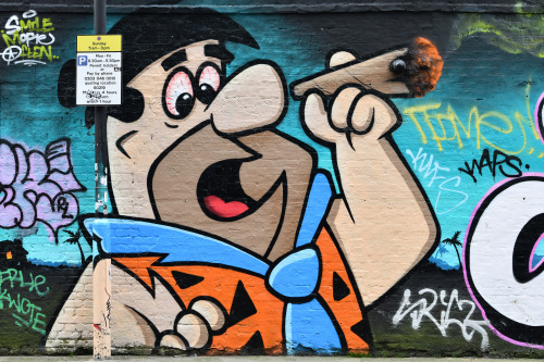 Fred Flintstone on a Shoreditch wall with blended in lamp post