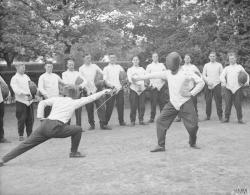 modernfencing:  [ID: two sabre fencers demonstrating parry two for a group of fencers.] A fencing class at the Aldershot Army Physical Training School, sometime between 1919 and 1939! © IWM (ARMY TRAINING 10/6) 