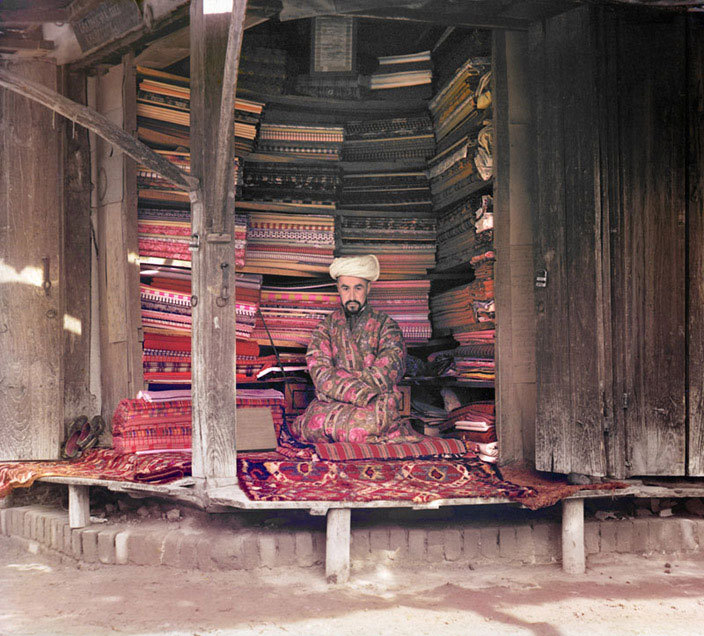 10  - chingizhobbes: A merchant at the Samarkand market displays colorful silk,