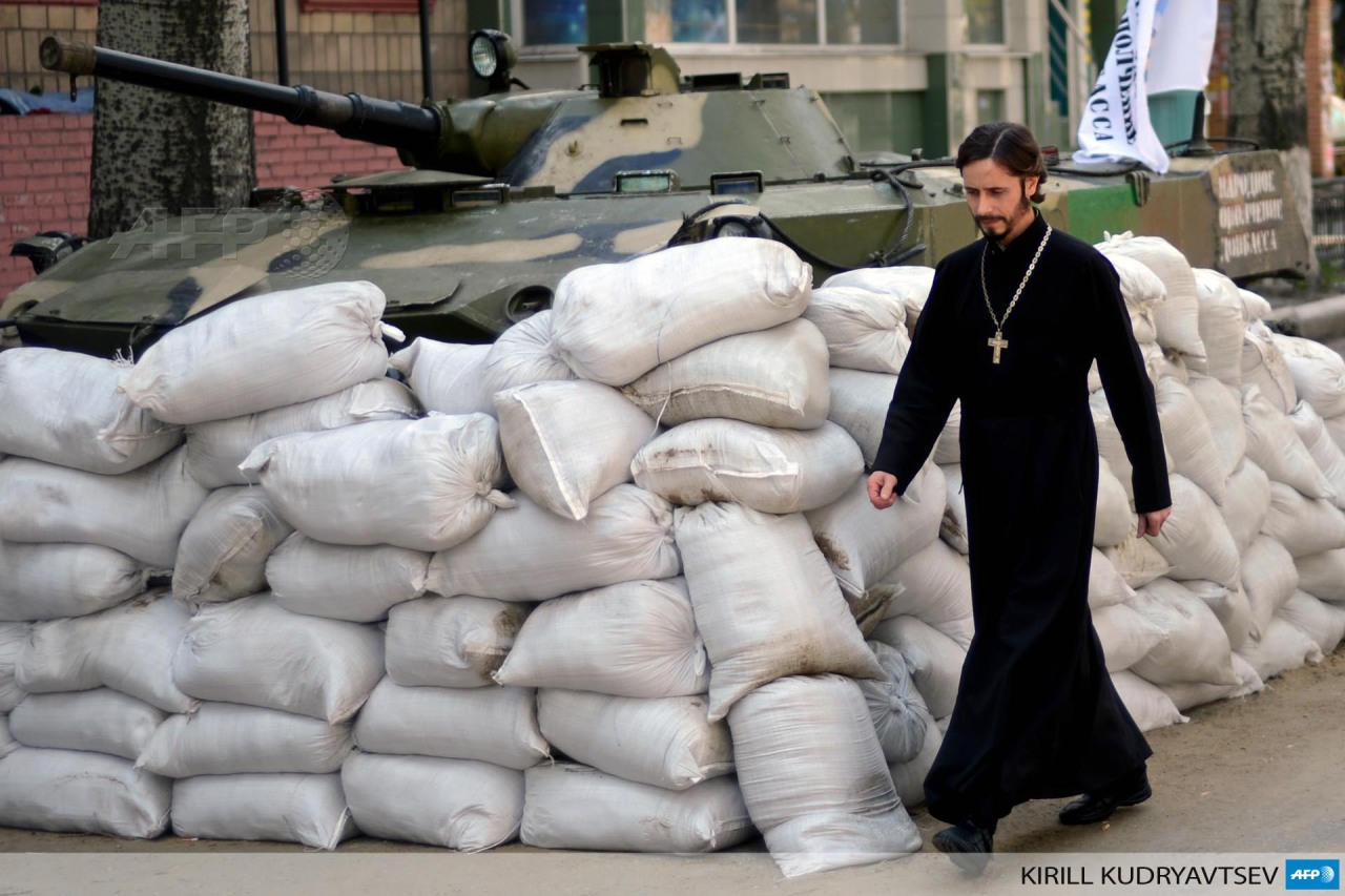 afp-photo:
“UKRAINE, Slavyansk : An Orthodox priest walks past a barricade outside the security service (SBU) regional building seized by the separatists in the eastern Ukrainian city of Slavyansk on April 23, 2014. Pro-Kremlin rebels in Ukraine...