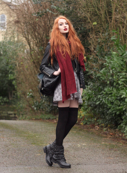 Olivia in black thigh high socks, combat boots, grey patterned skirt, leather jacket and bright red 