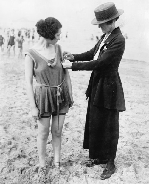 A police woman measures a bathing suit checking for length violations.  Chicago, Illinois. 1921