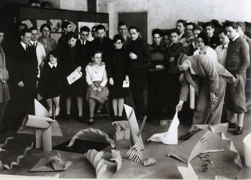 bauhaus-movement:
“Josef Albers Discussing Paper Sculptures presented by His Students during the Preliminary Course at the Bauhaus, Dessau, Germany (1928-1929). Photo by Umbo (Otto Umbehr) © The Joseph and Anni Albers Foundation
”