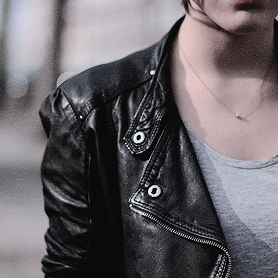 An image of a woman in a black leather jacket and grey t-shirt from the neck down