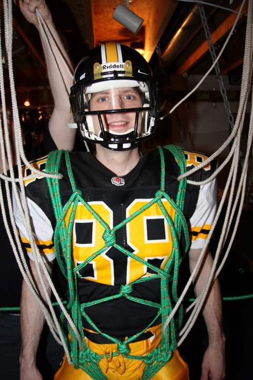 Getting strung up for a football bondage suspension scene in Hamilton Tiger Cats football gear.