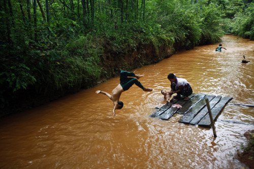 An ethnic Pa-O boy dives into the stream while his mother bathes a baby near Inle lake in Shan state