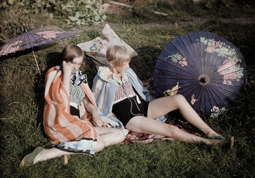 Two young girls enjoy the sun relaxing in their suits and wraps in England, September 1929.Photograp