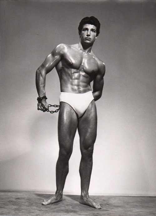 Photo of bodybuilder Charles Kassapian in chains by Gregor Arax, 1955