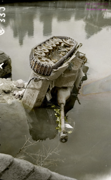 A German StuG III Ausf G assault gun lays on its side in the river at Putanges-Pont-Écrepin, 