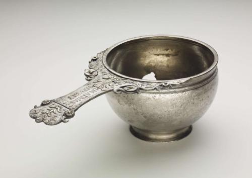 Silver skillet, with a highly decorated handle and some gilding.   The bowl is deep, with slightly i
