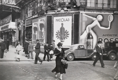 Parisians walk on the street past lottery and vermouth advertisements in 1935.Photograph by Maynard 