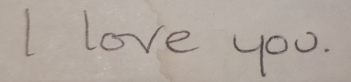 A handwritten note on a piece of slightly aged paper. It reads 'I love you.'