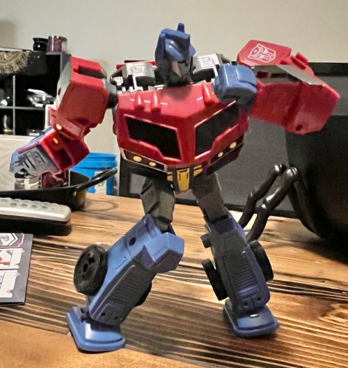 optimus prime with his knees facing inwards singing into an invisible microphone. he's doing disney knees. end text
