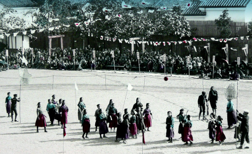 School girls playing a game with a ball and high nets - maybe a form of basketball?  Spectators look
