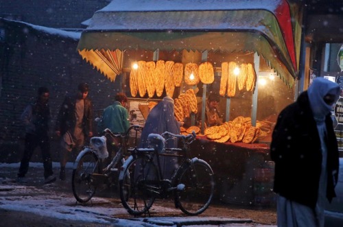 fotojournalismus:An Afghan woman buys bread from a street vendor during a snow storm in Kabul on Mar