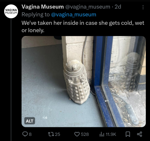 A tweet from the Vagina Museum reading "We've taken her inside in case she gets wet, sad, or lonely." Attached is a photo of the concrete dalek propped up next to a window.