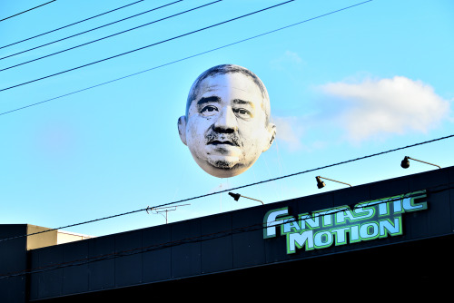 ofools:hollowedskin:shihlun:A giant helium balloon bearing the face of an ojisan (middle-aged man) a