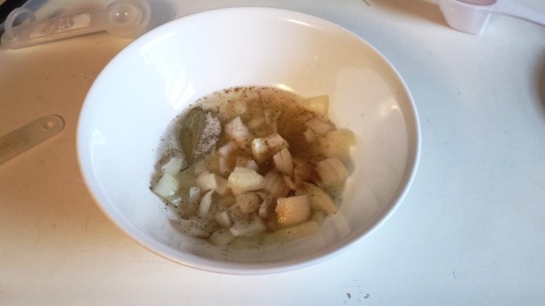 a small bowl of onion, pepper, cumin, bay leaf, and water.