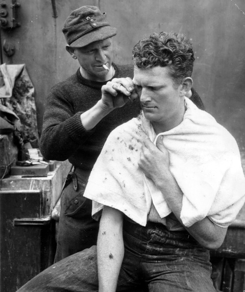 A German POW receives a haircut by a fellow captive aboard a US ship off the coast of Normandy - Jun