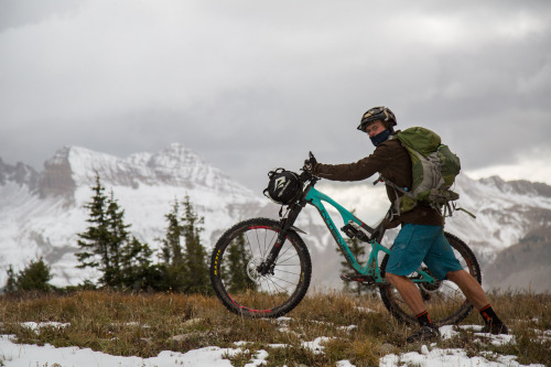 image of a cyclists pushing his bike up a snowy mountainside