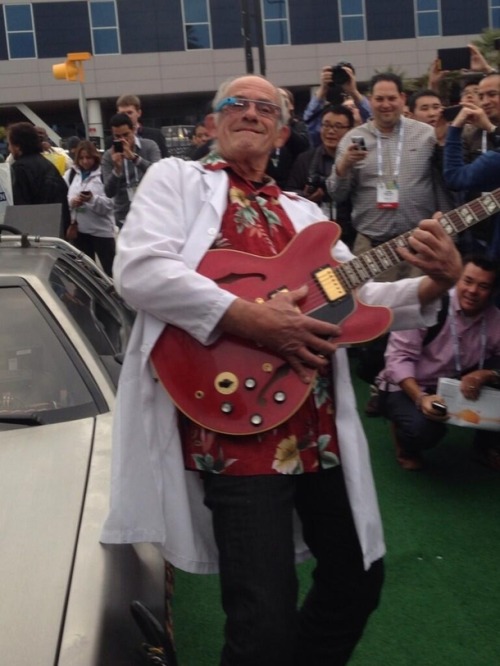 memeguy-com: Christopher Lloyd next to a DeLorean wearing Google Glass and playing Marty McFlys Gibs