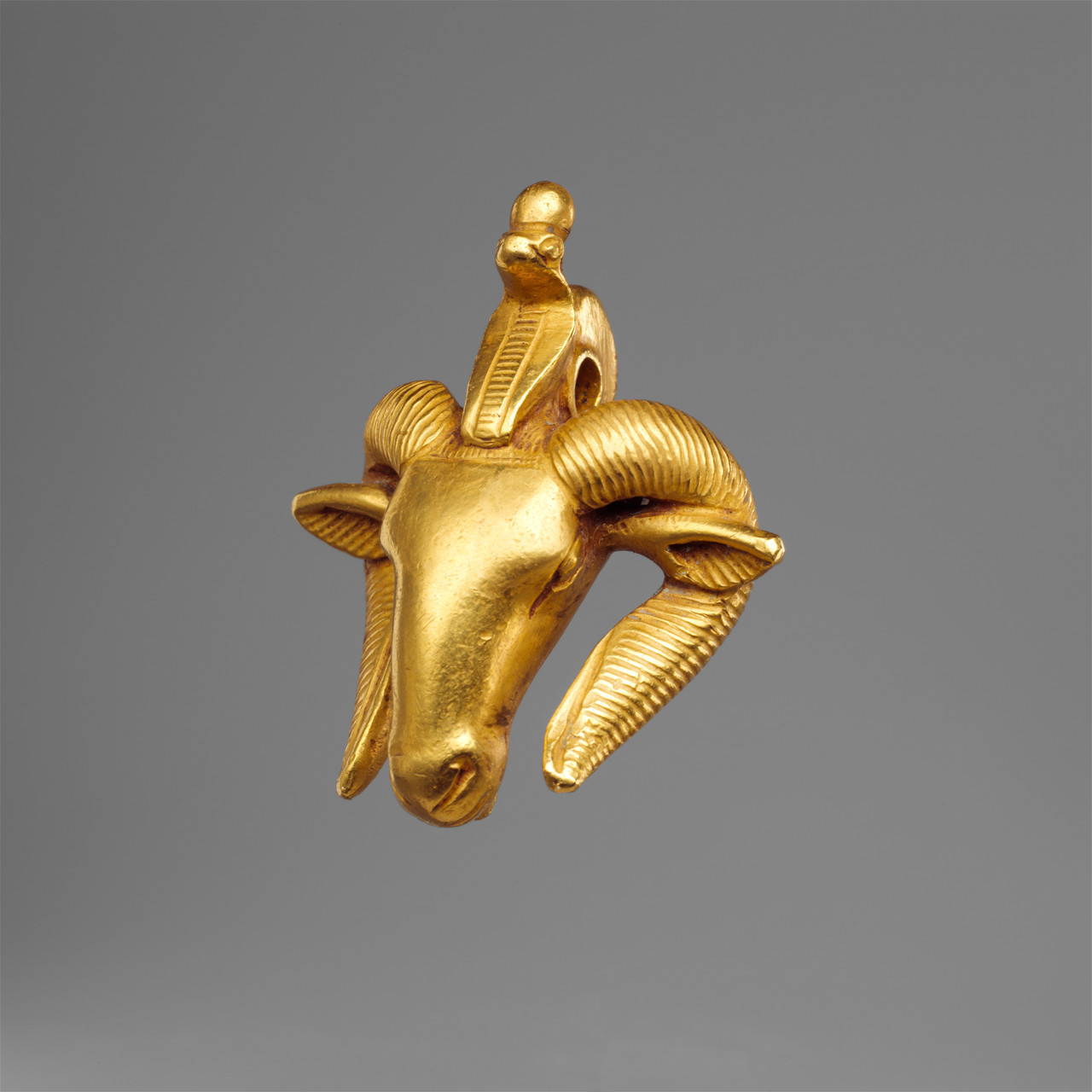 Ancient Egyptian gold amulet in the shape of a ram’s head. Artist ...